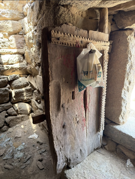 الباب الخشبي مع بقايا من لونه الأحمر الأصلي