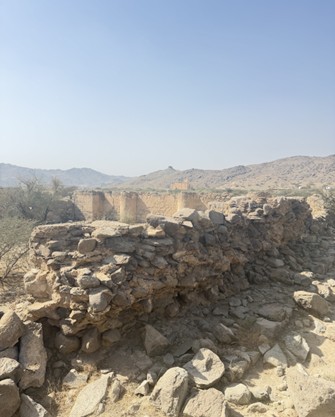 بقايا جدار حجري متهدم مع تراكم الأنقاض نتيجة العوامل الطبيعية