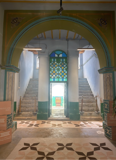 درجين مزدوجين يؤديان إلى حوش داخلي وممر رئيسي مسقوف مزود بأعمدة وأقواس